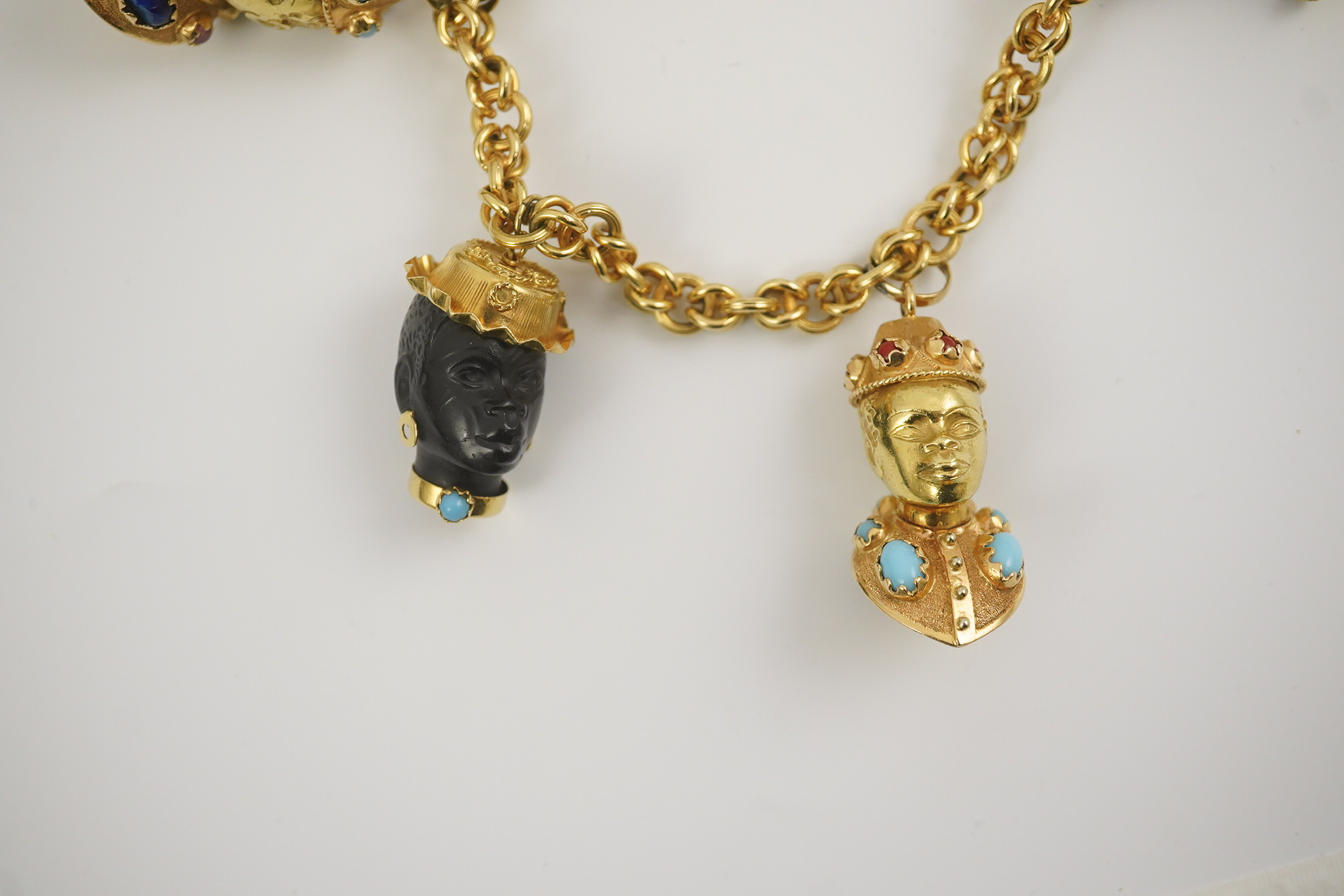 A late 20th century Italian 18k gold charm bracelet, hung with six assorted Italian 18k gold and gem set mounted blackamoor busts, together with a matching brooch